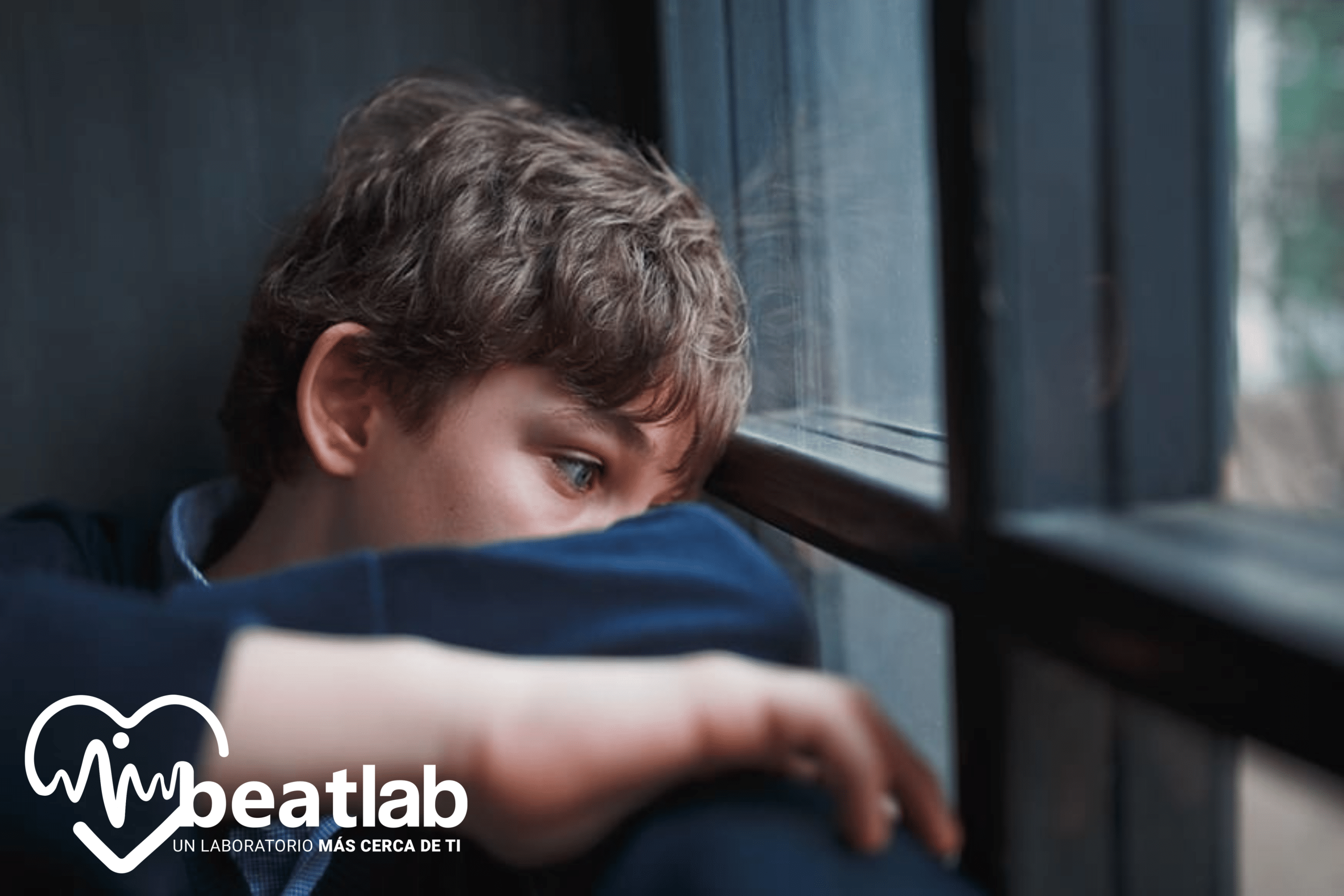 Adolescente apoyado en una ventana con expresión triste, representando señales tempranas de ansiedad y depresión en jóvenes